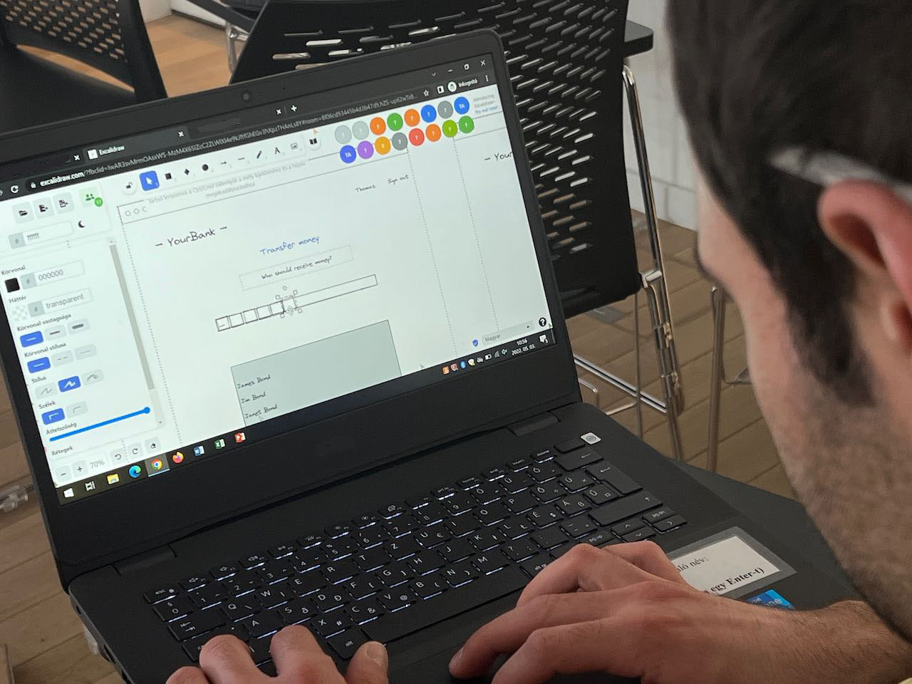 Egy tanteremben elhelyezett laptop képernyőjét mutatja a kép. A laptop képernyőjén látható, hogy egy kollaborációs felületen sok diák egyszerre dolgozik együtt.