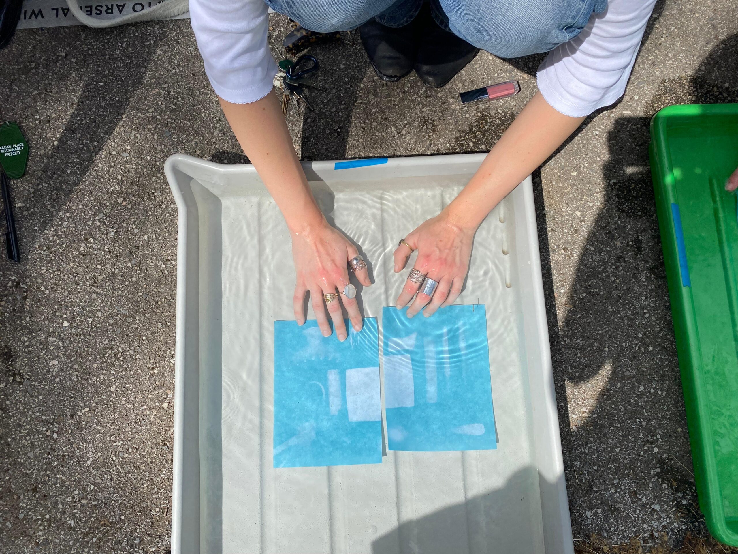 Teilnehmer*in entwickelt die belichteten Cyanotypie-Papiere in Wasserwanne